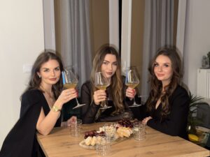 Trzy eleganckie kobiety wznoszące toast kieliszkami z białym winem podczas degustacji na wieczór panieński organizowanej przez Ta od Wina